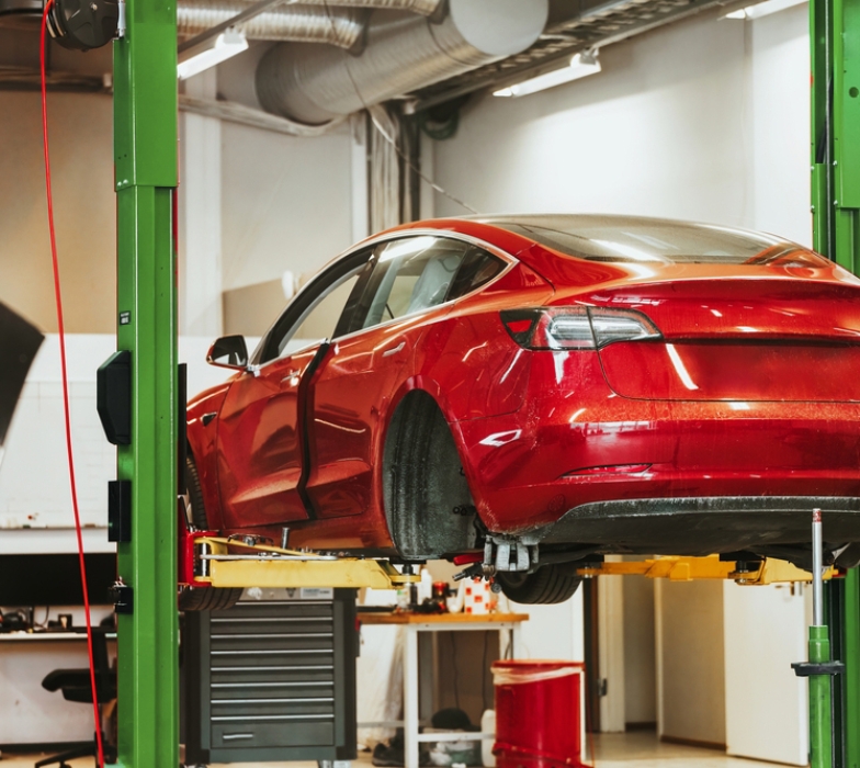 The rear hub of a car without a wheel. Removed wheel in the foreground. Electric vehicle maintenance at a Professional Workshop. Repairing the EV transport. Car lifted in auto service shop.
